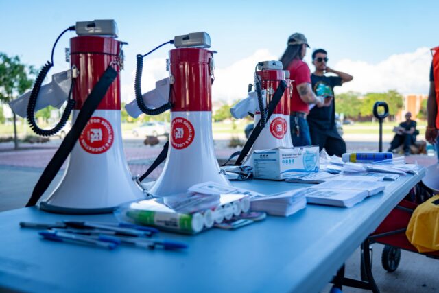 Protestors representing the Party for Socialism and Liberation came equipped with megaphones and signs ahead of their protest across from campus Wednesday. Sam Gassaway | Photo Editor