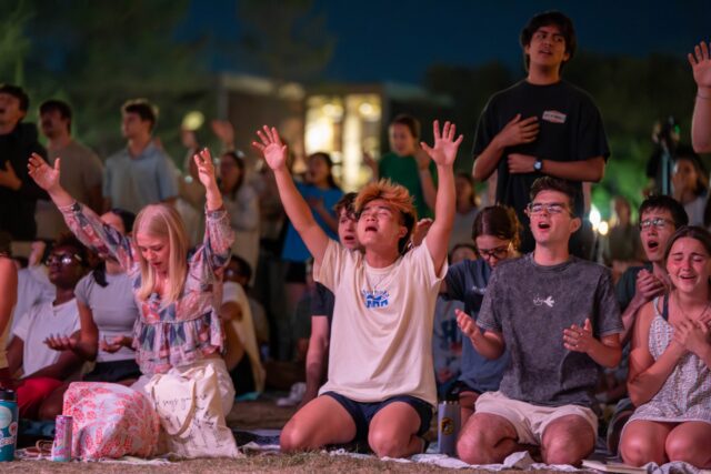 Students throw up their hands in praise at FM72 on Fountain Mall on Sunday night. Caleb Garcia | Photographer