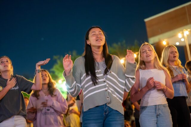 Attendees sing praises at the beginning of FM72 at Fountain Mall on Sunday night. Caleb Garcia | Photographer