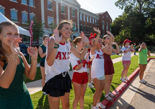 Students from Alpha Chi Omega cheer as cars pull into Kokernot hall. Mesha Mittanasala | Photographer